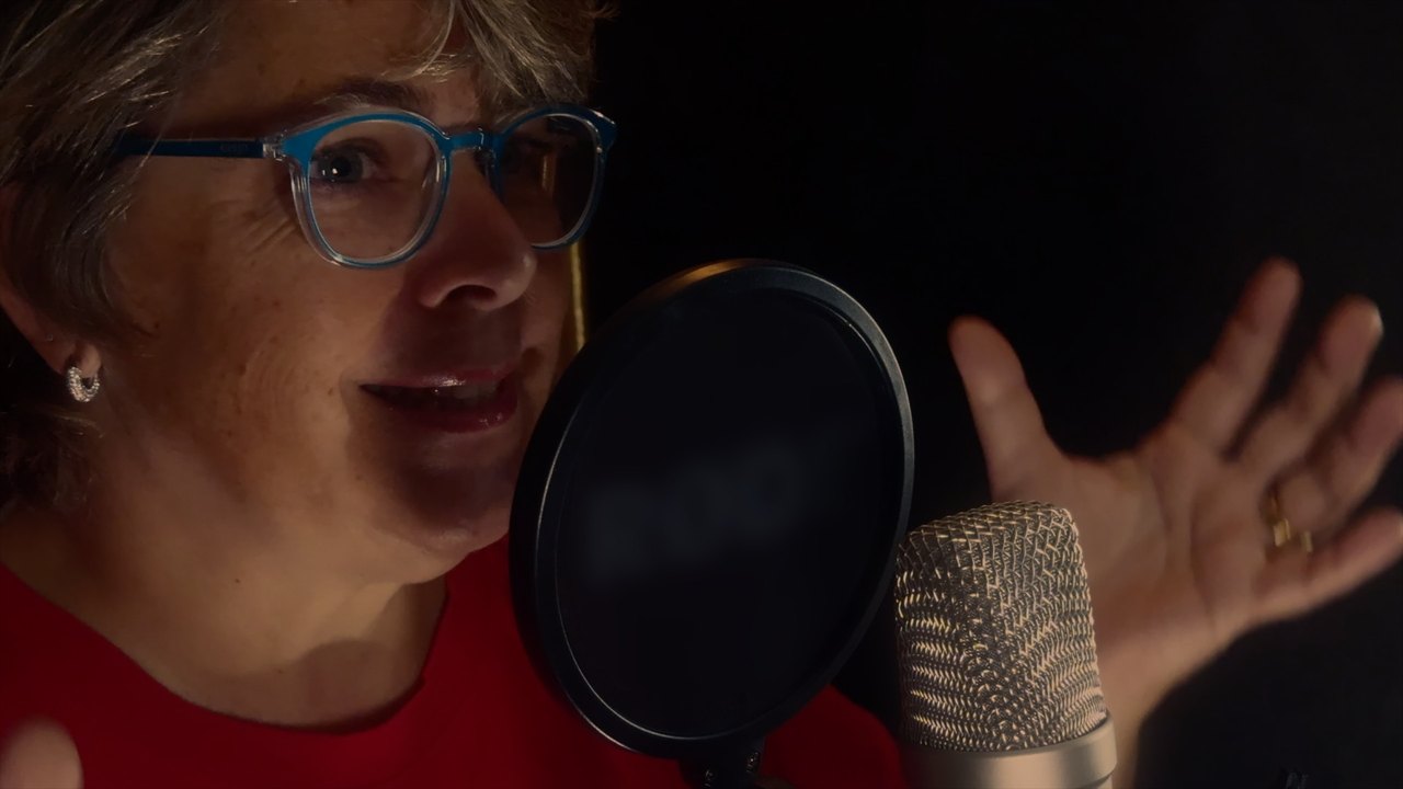 Sprecherin am Studiomikrofon mit Popschutz während einer Podcast-Aufnahme